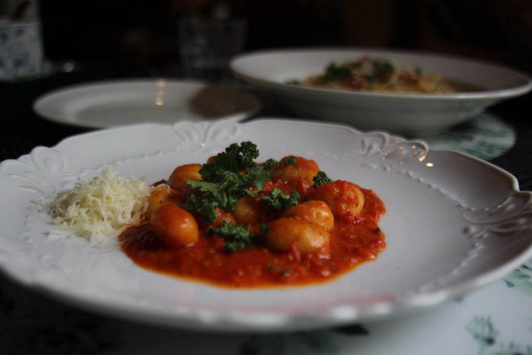 1ED3DC19-1A33-489C-905C-C391A2624B2E_1_105_c Close-up of gnocchi in rich tomato sauce topped with fresh parsley and grated cheese, served on an elegant white plate — authentic Italian pasta dish at a cozy Hakuba mountain café. Ask ChatGPT