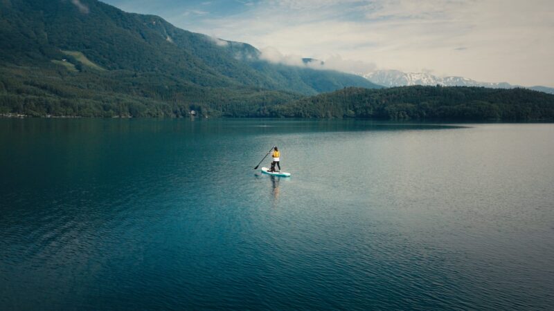 paddleboarding on Lake Aoki by Lakeside Cafe Ao with forested mountains and snow-capped peaks in Hakuba, Japan