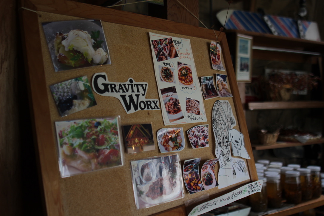 BB9780DF-2C35-4A18-B2B5-8FD23ED693A3_1_105_c Bulletin board at Gravity Worx Hakuba showcasing colorful food photos, handwritten menu items, and playful illustrations — highlighting the café’s homemade pasta dishes, seasonal specials, and cozy mountain vibe with jars of aged chili oil displayed nearby.