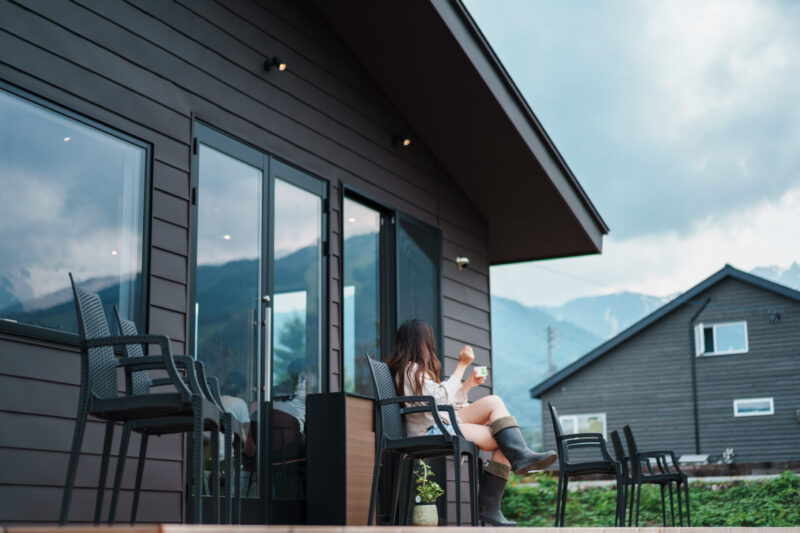 Woman enjoying gelato on the outdoor terrace at TABITABI Café in Hakuba, Nagano, with scenic views of the Japanese Alps in Hakuba in the background