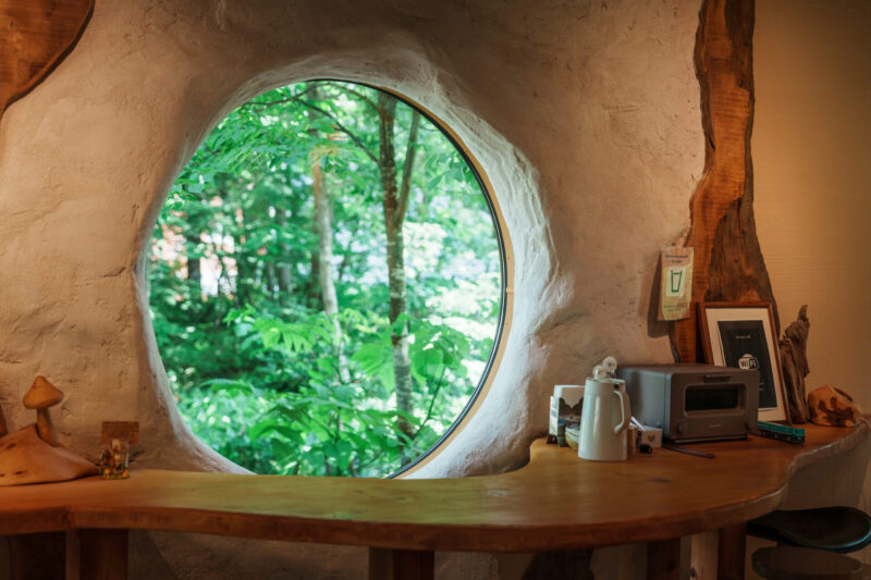 Round window with forest view in rustic café interior with wooden counter and decor