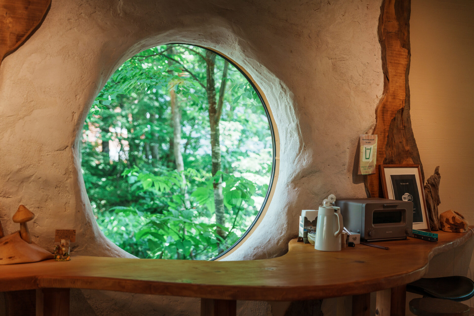 Round window with forest view in rustic café interior with wooden counter and decor