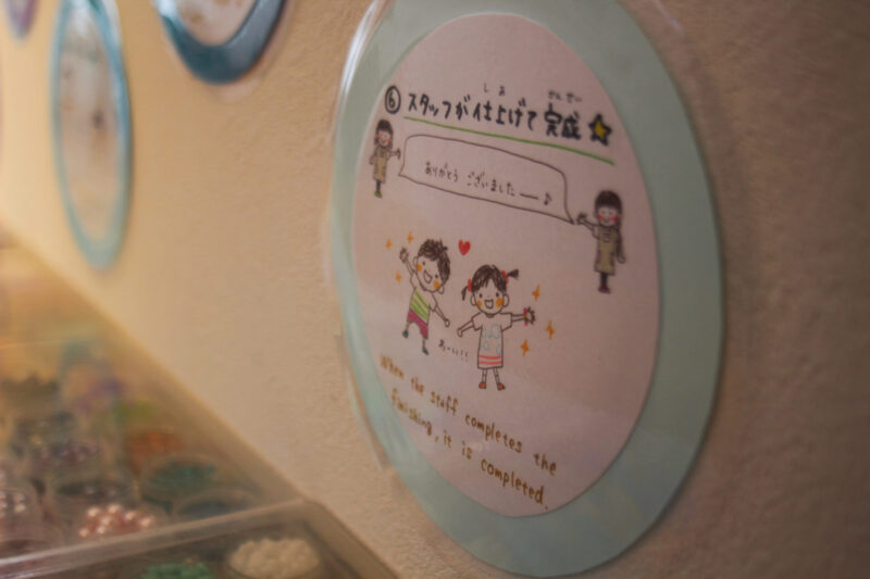 One friendly sign that reminds children to ask for staff assistance when the beads are long enough to fit around their wrist—making the experience easy to follow, even for little ones or non-Japanese speakers.