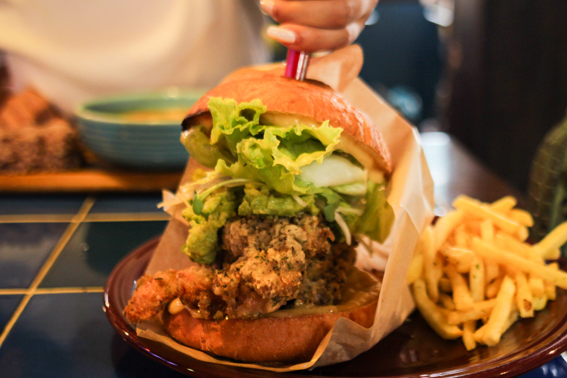 IMG_2775 Towering chicken burger with avocado, lettuce, and herbs served at Sounds Like Café Hakuba, known for the biggest burgers in Echoland.