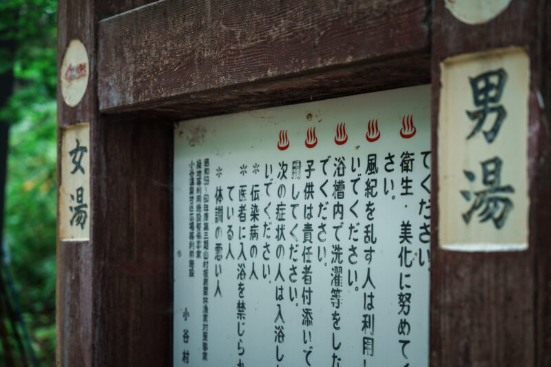 Sign above stone steps leading to Amakazari Kogen Onsen from the mountain road in Otari