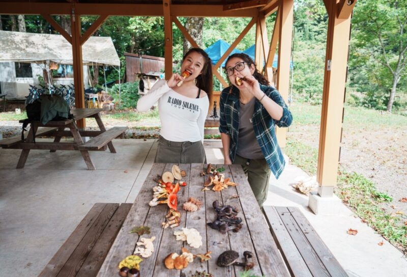 Two girls displaying the various types of mushrooms they collected in Otari, Nagano, Japan