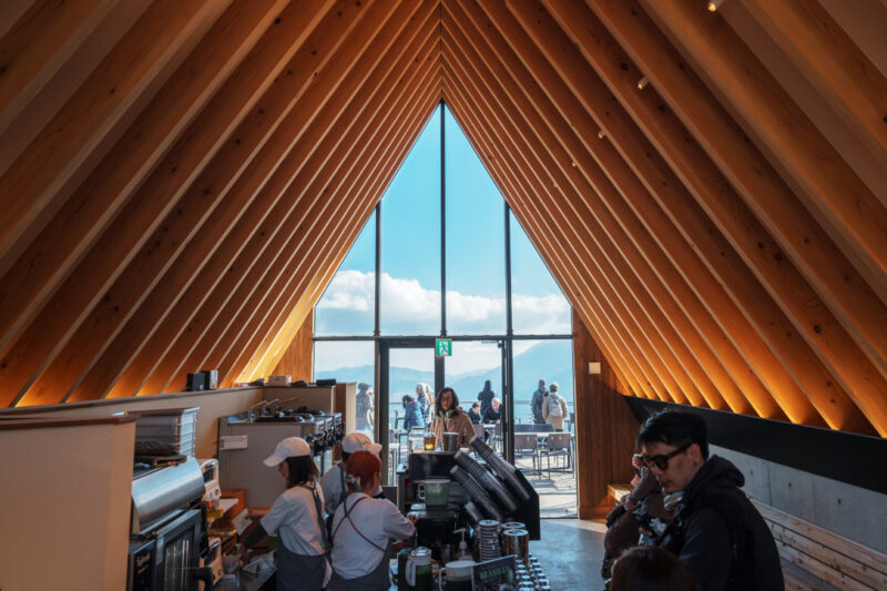 Modern triangular-roof interior of CHAVATY HAKUBA, a scenic tea latte café in the Japanese Alps, featuring floor-to-ceiling windows with panoramic mountain views and a stylish wood-beamed design — a must-visit spot for tea lovers and architecture enthusiasts in Hakuba.