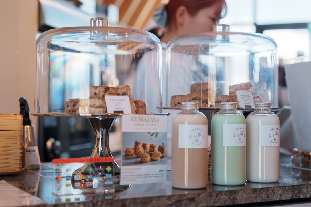 7F099BFD-292A-4384-853A-C93E0F233A5B_1_105_c CHAVATY HAKUBA’s counter display featuring freshly baked scones under glass domes and bottled milk tea lattes in houjicha, matcha, and original flavors — a stylish tea latte café in Hakuba known for artisanal sweets and Japanese tea culture.