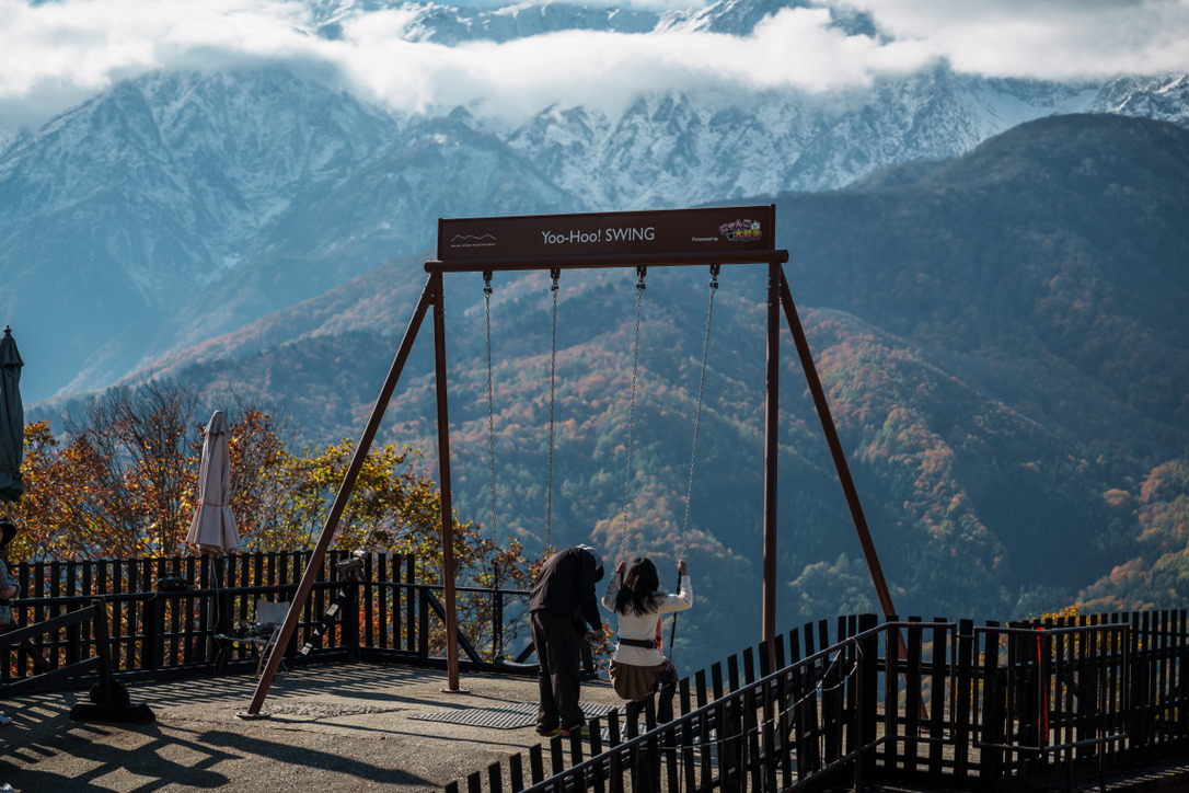 B4F52771-179D-441C-B64E-F1A03B36E2D6_1_105_c Two women wearing life jackets prepare for stand-up paddleboarding on Lake Aoki in Hakuba, Nagano, Japan, with turquoise waters and mountains in the background.